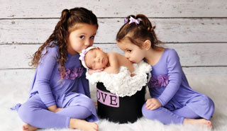 Twins kissing sleeping baby